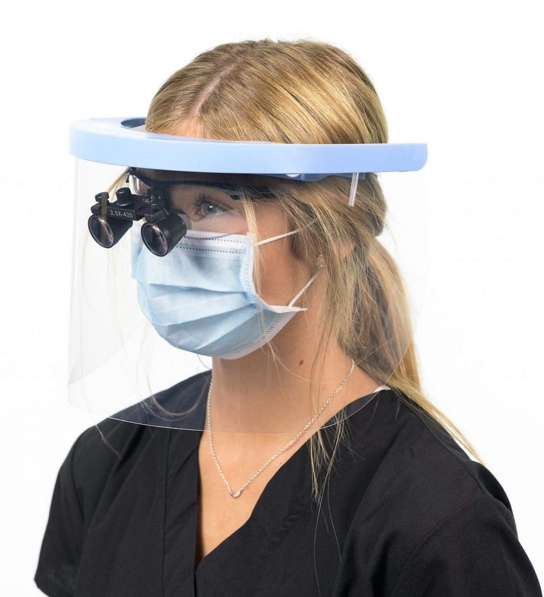 A woman wearing a face shield, mask, and surgical loupe glasses.