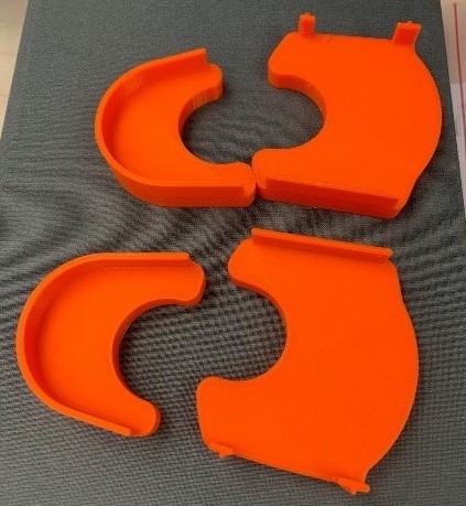 3D printed orange shoe covers used for correcting abnormal foot curvature in babies.